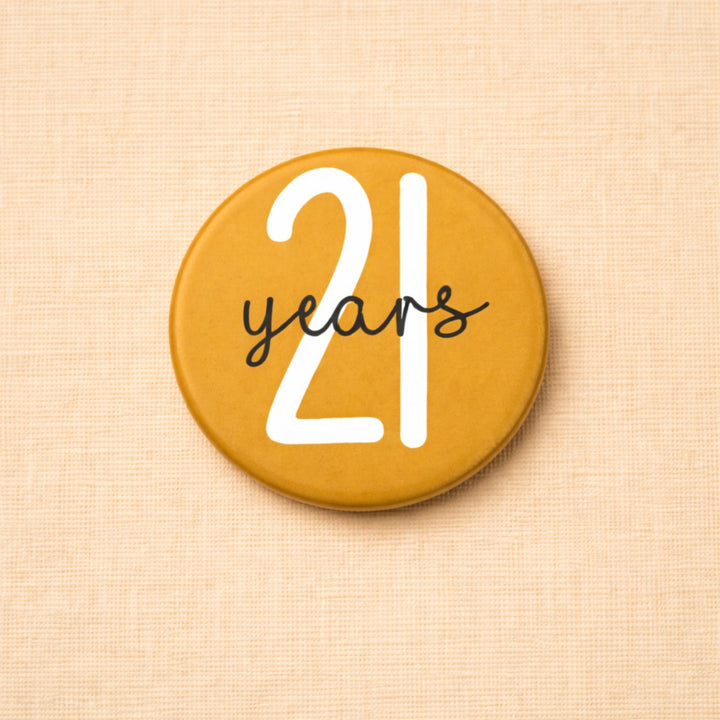 Okergele verjaardag button met de tekst “21 years” in speelse typografie, een feestelijke button voor een 21e verjaardag.