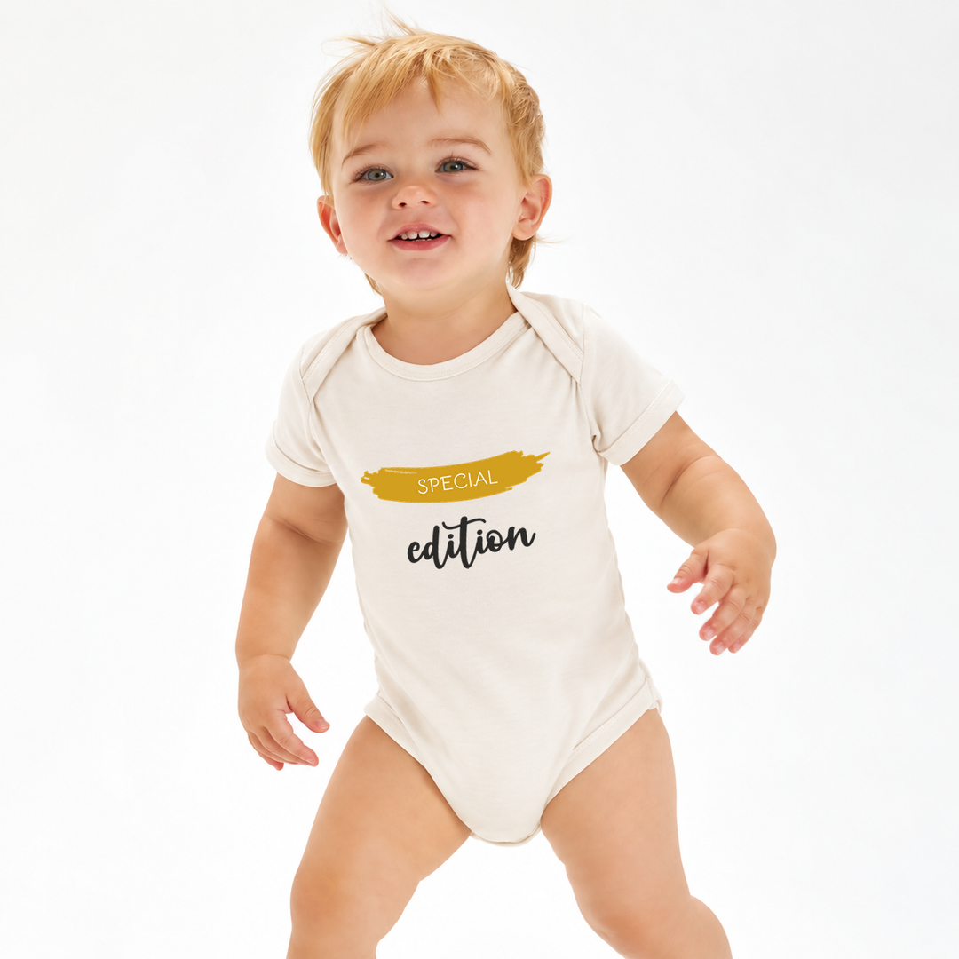 Baby draagt naturel rompertje met Special Edition tekst.