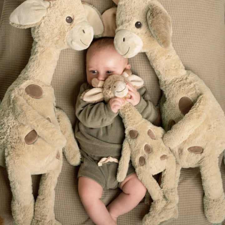 Baby met meerdere zachte Happy Horse giraffe knuffels, perfect als kraamcadeau
