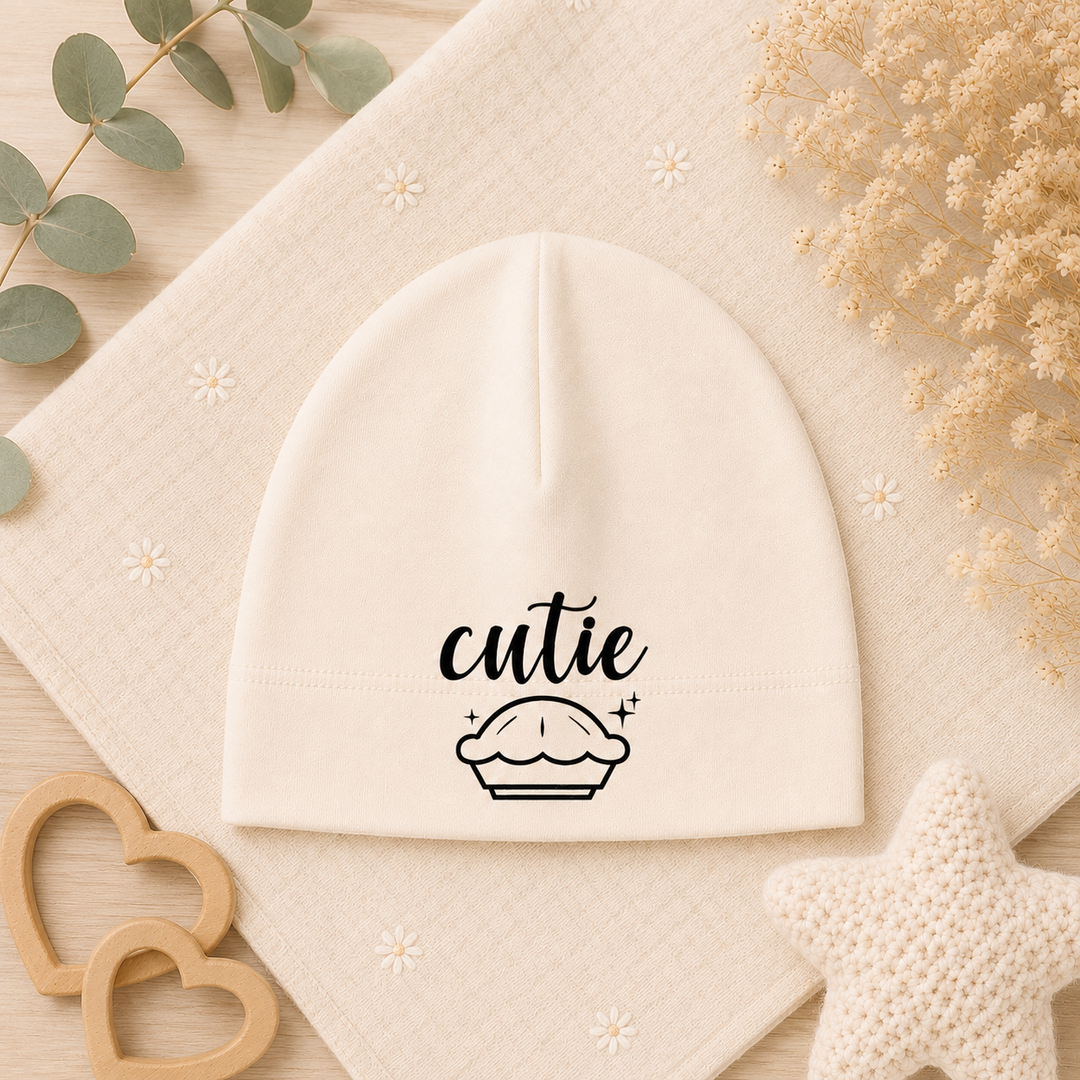 Organic babymutsje beige met opdruk “cutie” en cupcake, newborn baby beanie als kraamcadeau