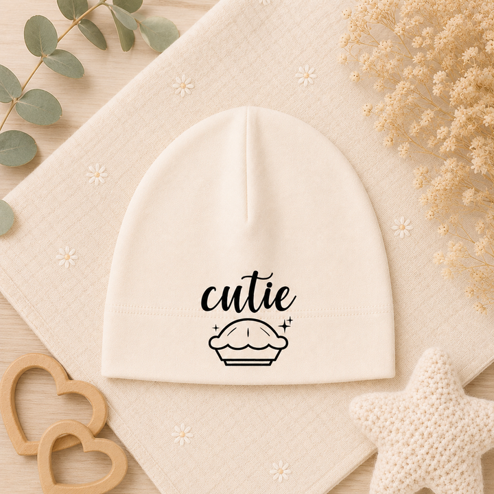 Organic babymutsje beige met opdruk “cutie” en cupcake, newborn baby beanie als kraamcadeau