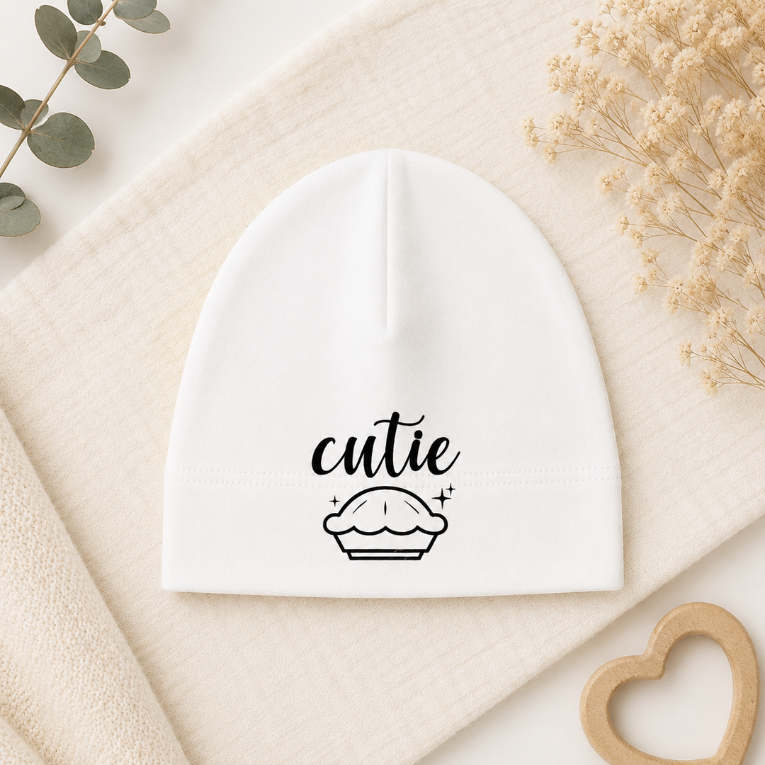 Wit newborn babymutsje met “cutie” cupcake opdruk, zachte beanie van organic katoen