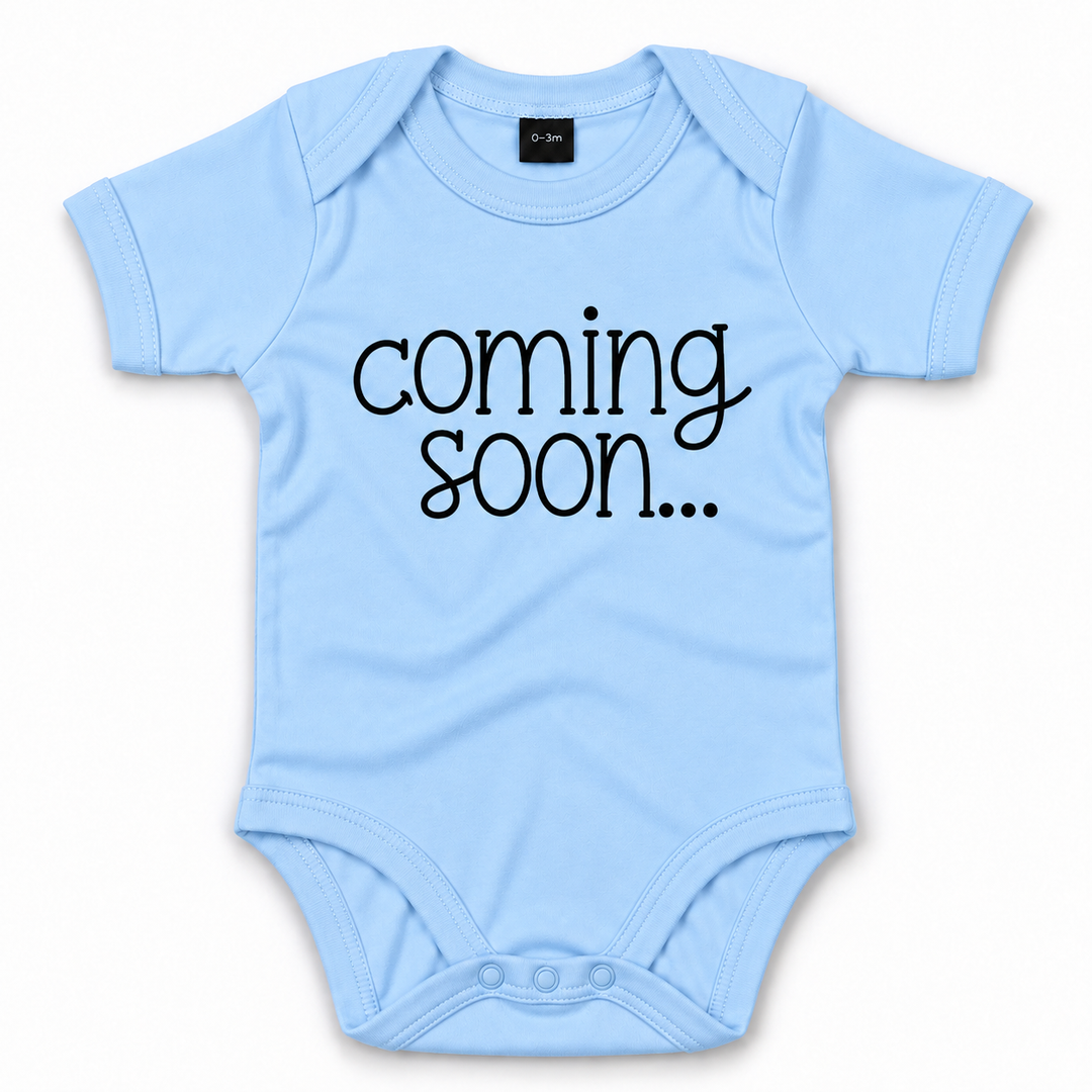 Blauw babyrompertje met zwarte tekst Coming Soon voor zwangerschapsaankondiging