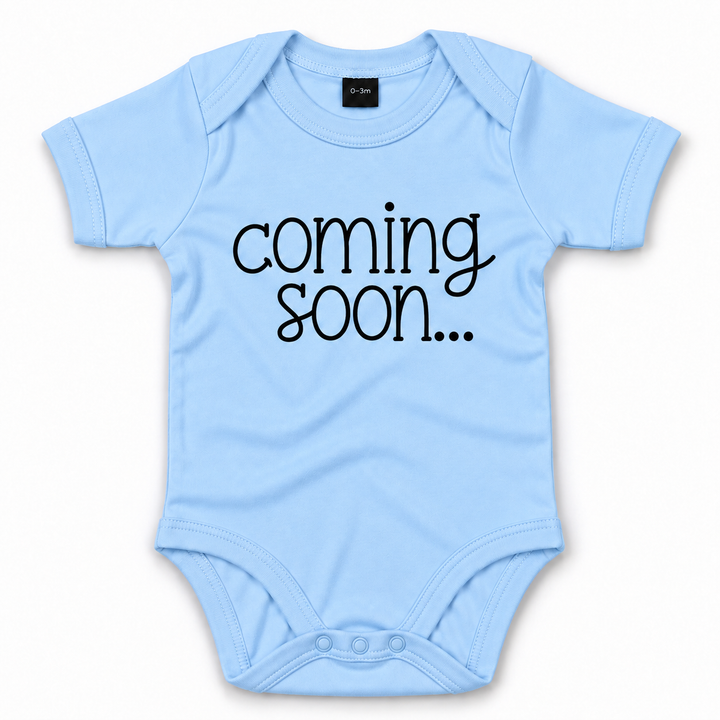 Blauw babyrompertje met zwarte tekst Coming Soon voor zwangerschapsaankondiging