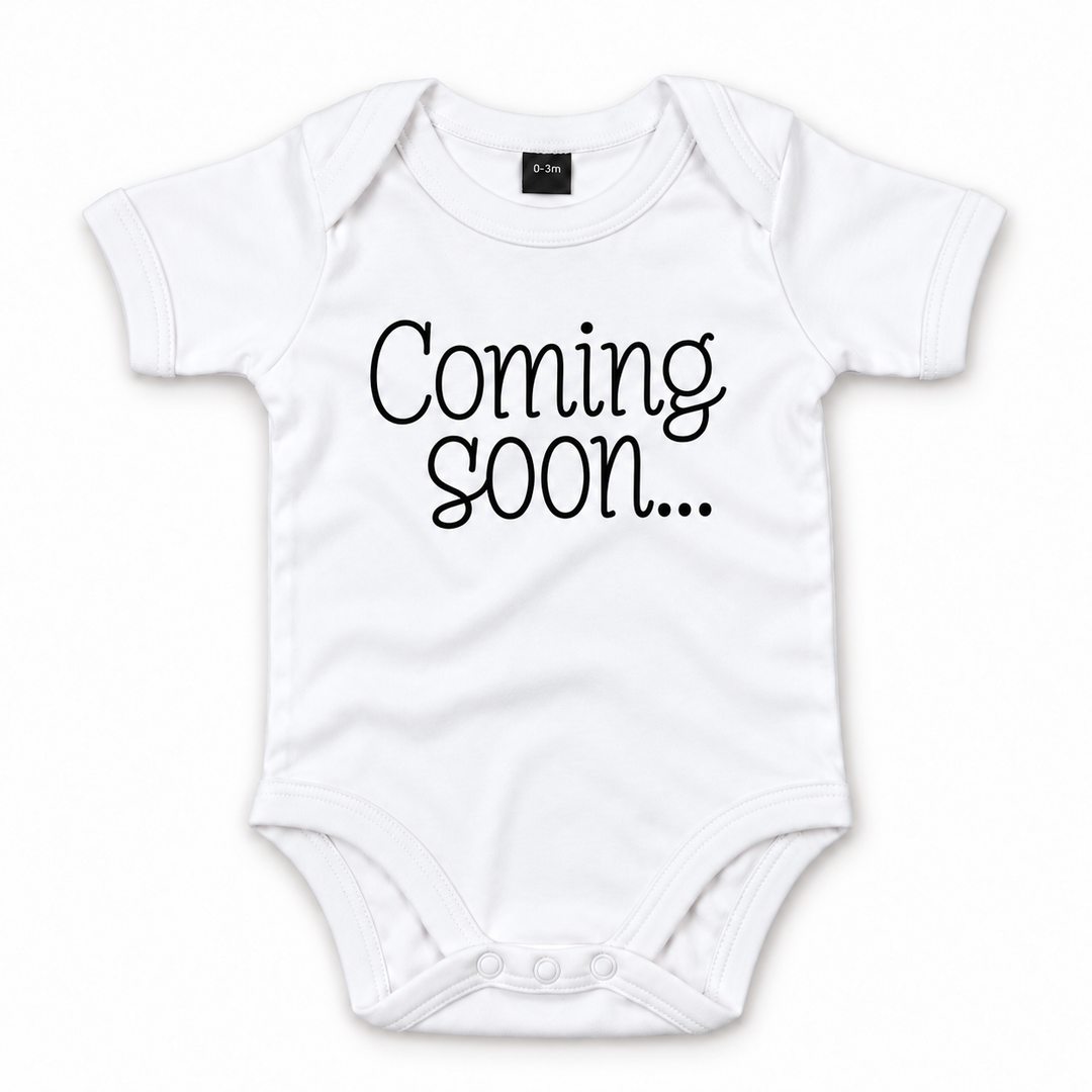 Wit babyrompertje met zwarte tekst Coming Soon voor zwangerschapsaankondiging