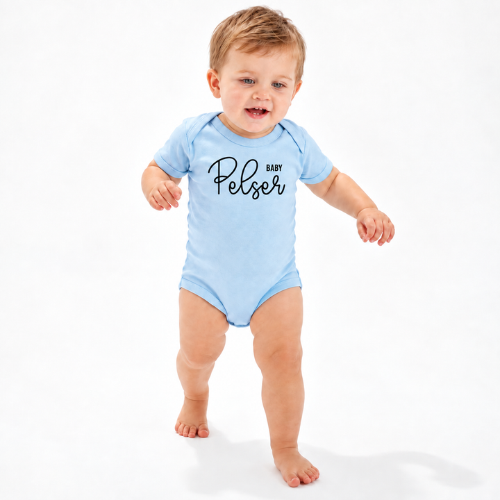 Baby draagt blauwe gepersonaliseerde romper met zwarte naamopdruk.