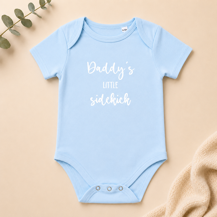 Baby rompertje “Daddy’s little sidekick” in baby blauw, organic katoenen rompertje met tekst voor zwangerschapsaankondiging en kraamcadeau