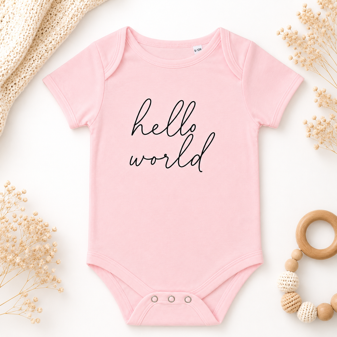 Roze babyrompertje met tekst “hello world”, organic katoen, geschikt als zwangerschapsaankondiging en babycadeau