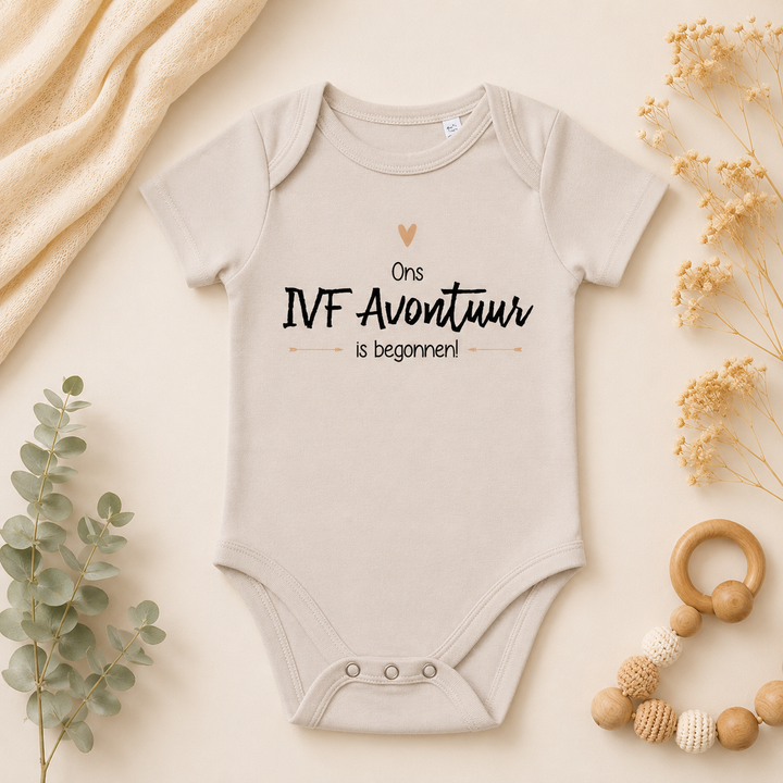 Beige babyrompertje met tekst “Ons IVF avontuur is begonnen” – IVF rompertje zwangerschapsaankondiging