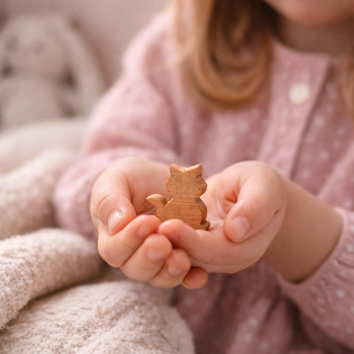 Meisje houdt handgemaakt houten katje vast