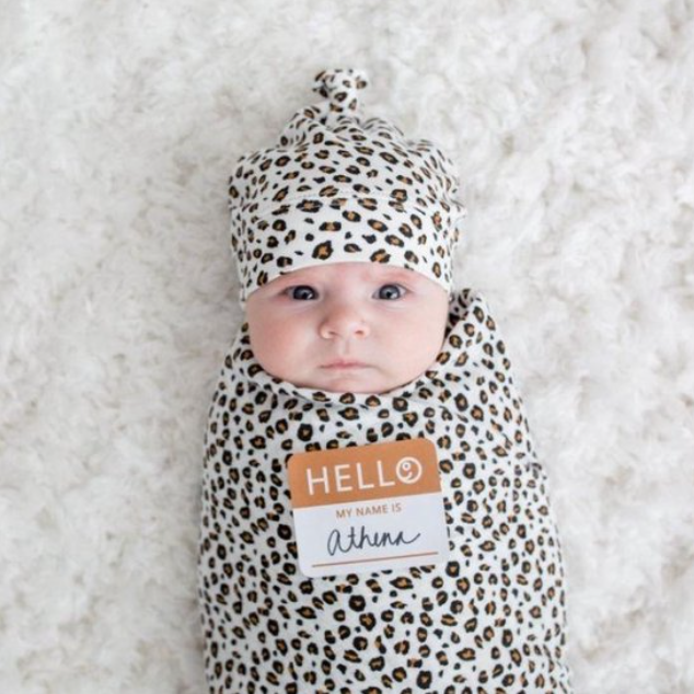 Newborn baby ingepakt in Lulujo Hello World swaddle leopard met bijpassend mutsje en Hello geboortesticker, ideaal als kraamcadeau