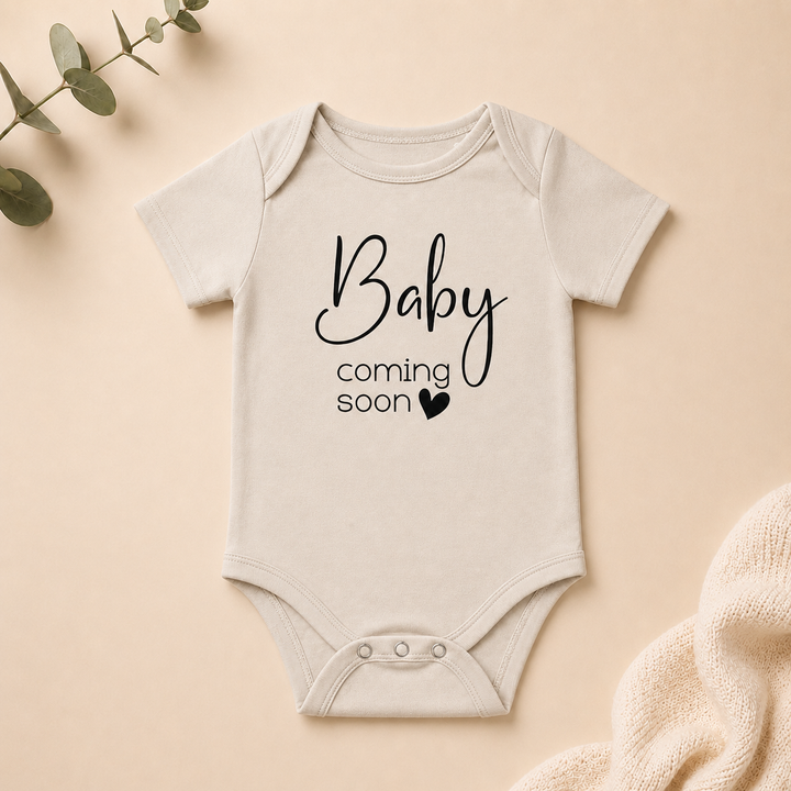 Naturel rompertje met tekst “Baby coming soon”, ideaal voor zwangerschapsaankondiging en babyshower