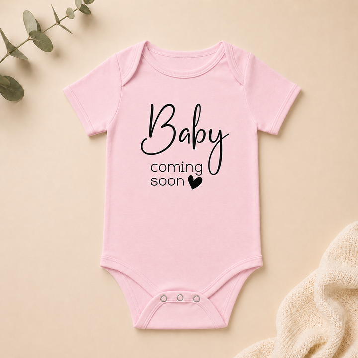 Rompertje met tekst “Baby coming soon” in roze, perfect als originele zwangerschapsaankondiging