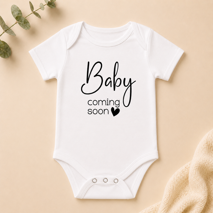 Wit rompertje “Baby coming soon” als originele zwangerschapsaankondiging voor (schoon)ouders