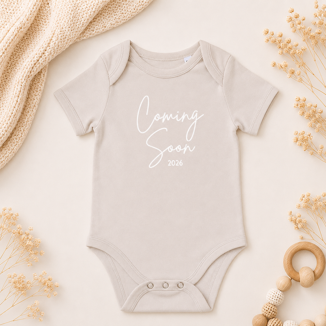 Beige rompertje met tekst “Coming Soon” als zwangerschapsaankondiging, organic katoen baby romper met tekst
