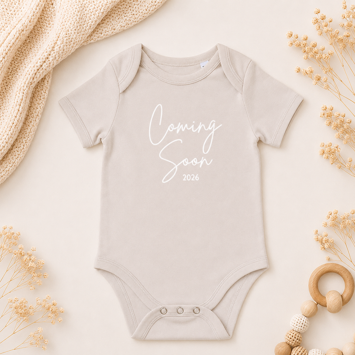 Beige rompertje met tekst “Coming Soon” als zwangerschapsaankondiging, organic katoen baby romper met tekst