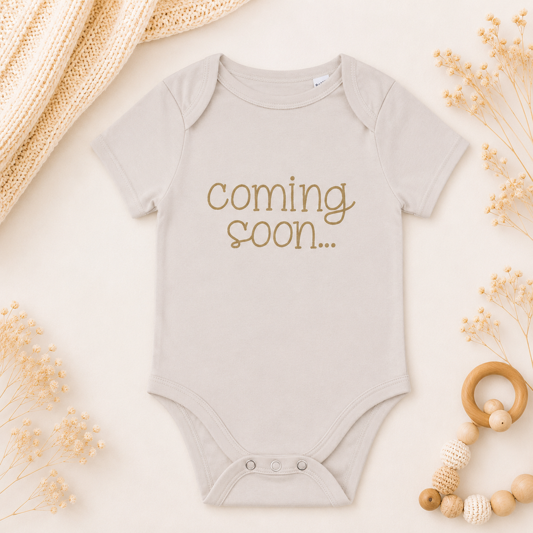 Rompertje “Coming soon…” voor zwangerschapsaankondiging, babyromper van organic katoen in beige kleur