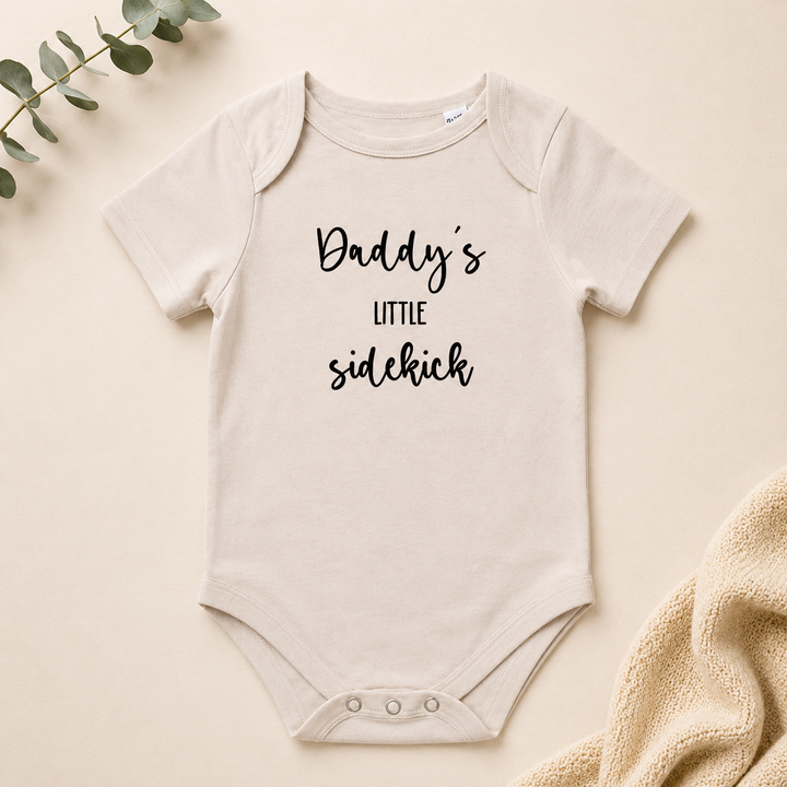 Beige organic baby rompertje “Daddy’s little sidekick” ideaal voor originele zwangerschapsaankondiging