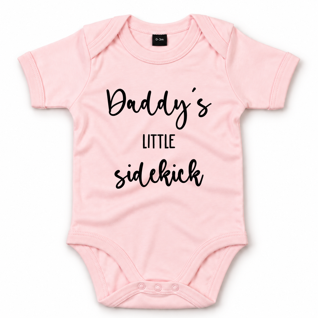 Roze baby romper met zwarte tekst Daddy’s Little Sidekick.