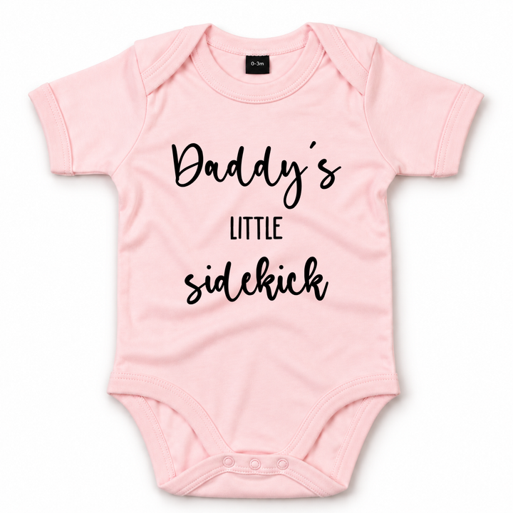 Roze baby romper met zwarte tekst Daddy’s Little Sidekick.