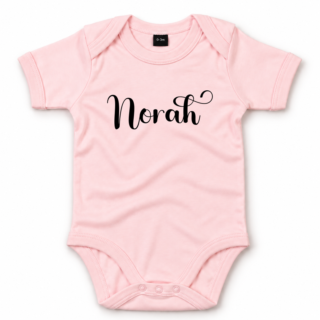Babyroze romper met naam Norah bedrukt op de voorkant.