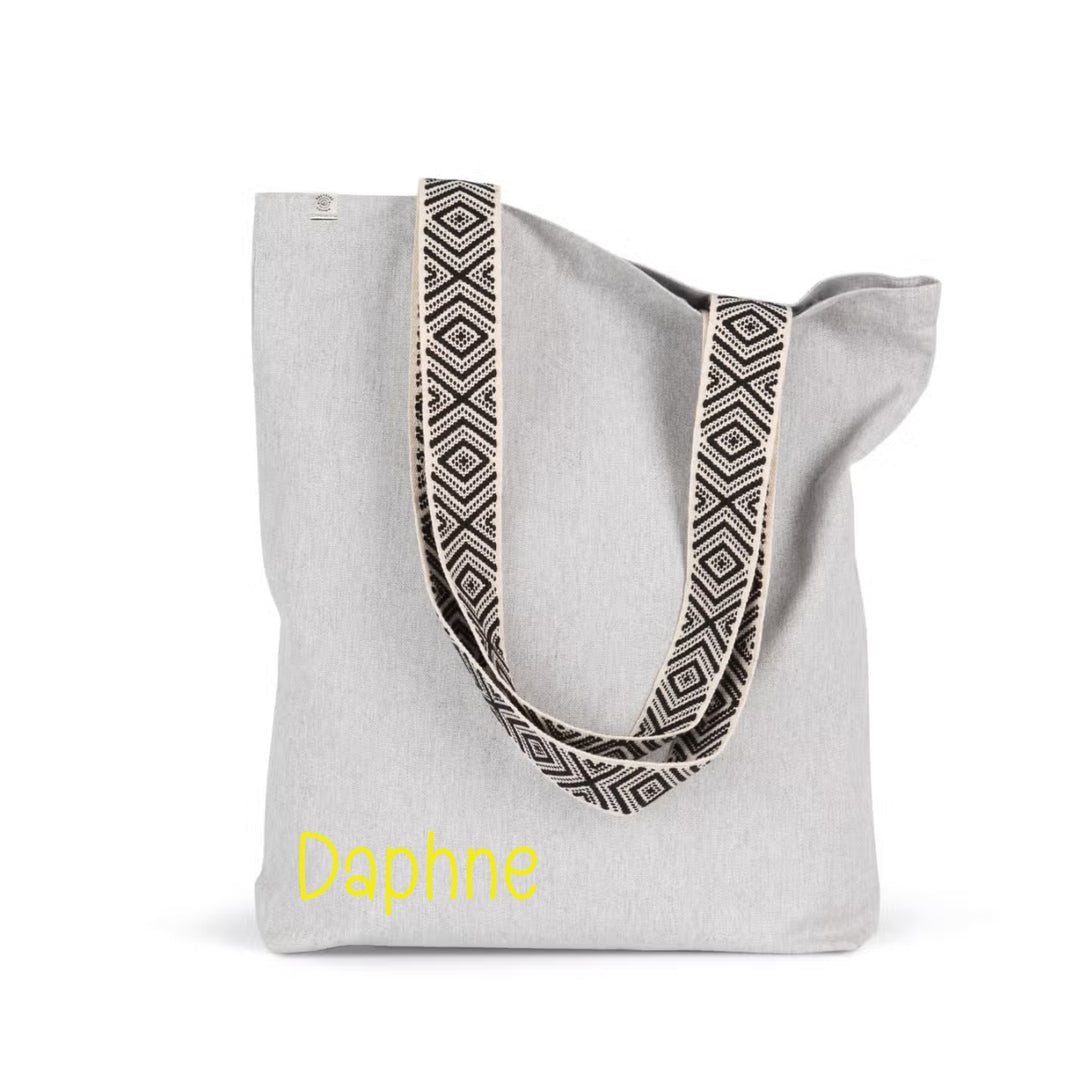 Gepersonaliseerde shopper met naam Daphne in gele opdruk op grijze linnen shopper met patroonbanden