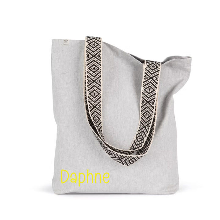 Gepersonaliseerde shopper met naam Daphne in gele opdruk op grijze linnen shopper met patroonbanden