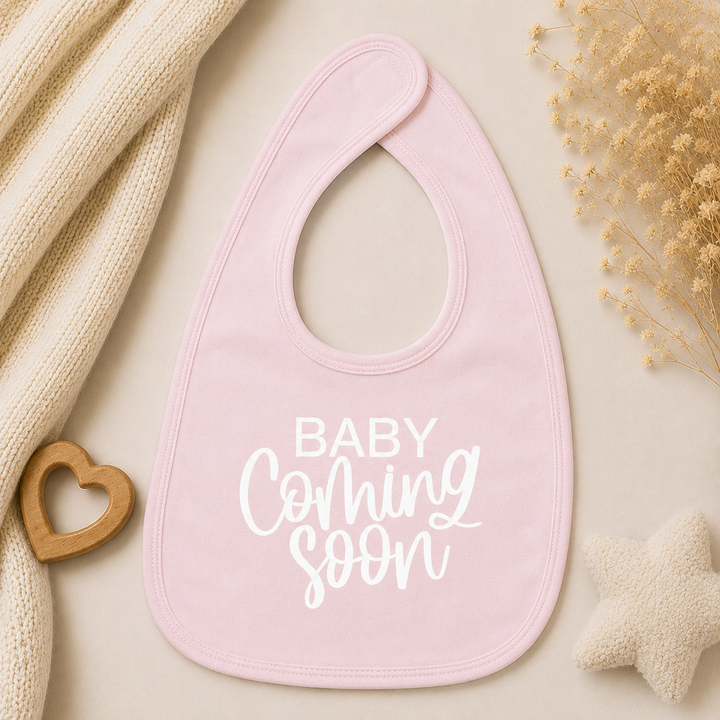 Babyroze slabbetje met opdruk “Baby coming soon”, origineel cadeau voor zwangerschapsaankondiging