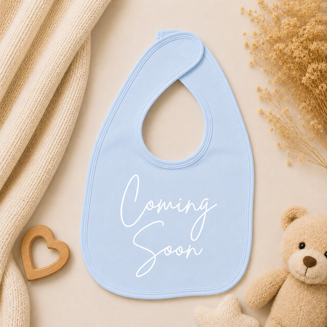 Blauw slabbetje met tekst “Coming soon”, lief cadeau voor zwangerschapsaankondiging op social media