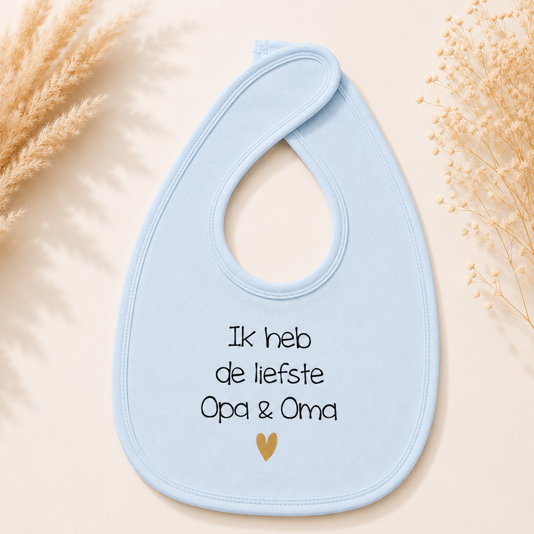 Blauw baby slabbetje met tekst “Ik heb de liefste opa & oma” en goud hartje, ideaal als zwangerschapsaankondiging voor opa en oma