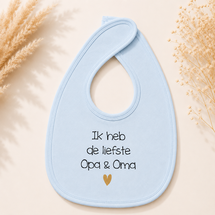 Blauw baby slabbetje met tekst “Ik heb de liefste opa & oma” en goud hartje, ideaal als zwangerschapsaankondiging voor opa en oma