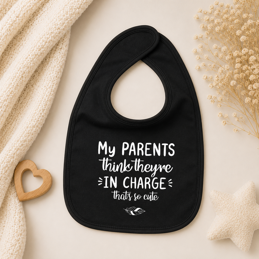 Zwart baby slabbetje met tekst “My parents think they’re in charge, that’s so cute” – grappig slabbetje met tekst