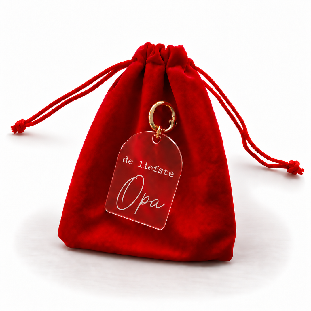 Transparante sleutelhanger met tekst de liefste opa en goudkleurige ring bij rood cadeauzakje.