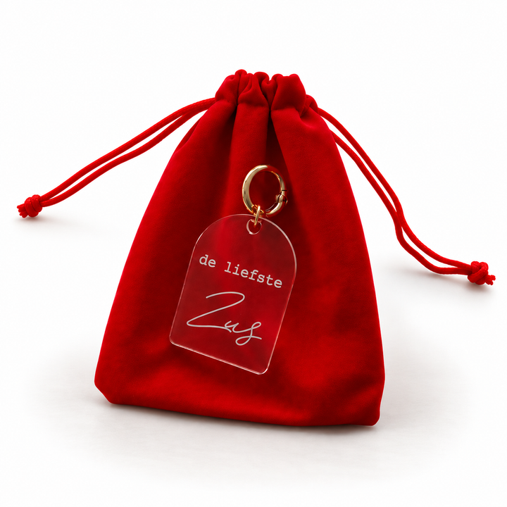 Persoonlijke sleutelhanger met tekst de liefste zus aan rood cadeauzakje.