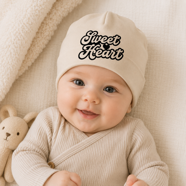 Baby draagt babymutsje “Sweet Heart”, zacht organic mutsje als kraamcadeau of newborn accessoire