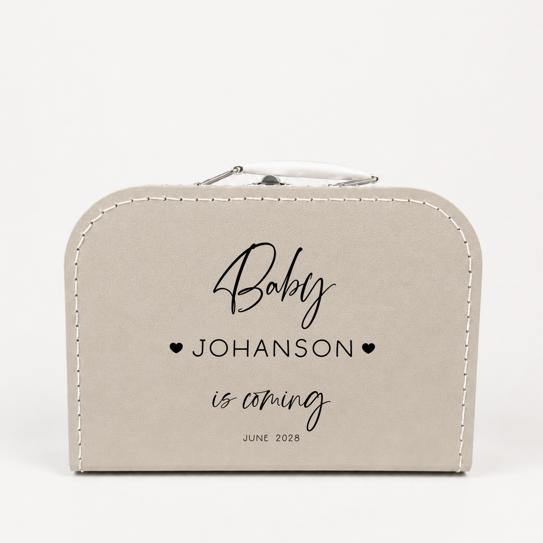 Close-up van zwangerschapsaankondiging koffertje “Baby is coming” gepersonaliseerd met naam en datum