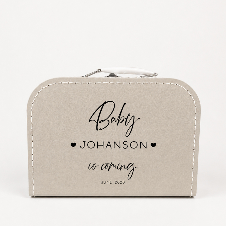 Close-up van zwangerschapsaankondiging koffertje “Baby is coming” gepersonaliseerd met naam en datum
