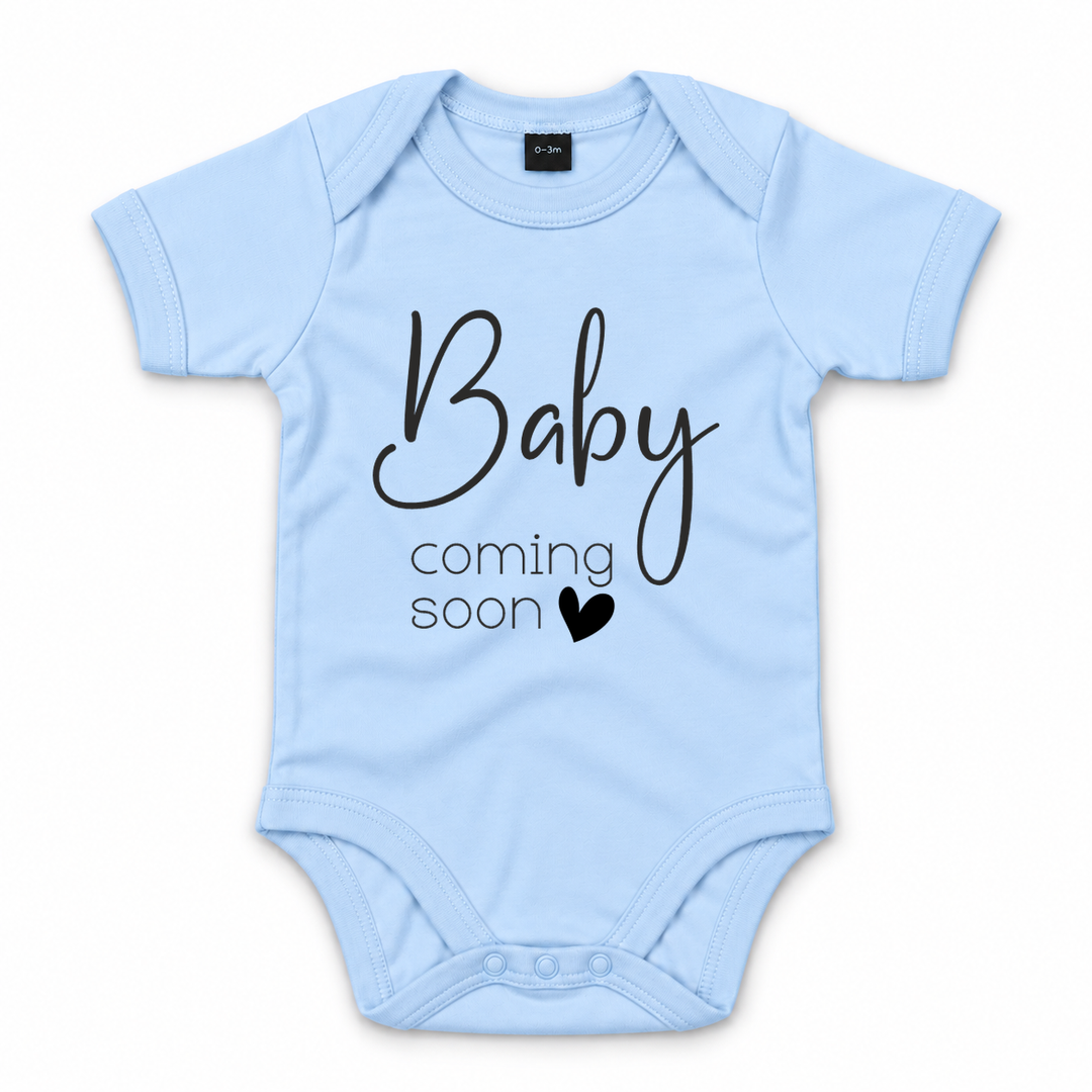 Blauwe zwangerschapsaankondiging romper met zwarte tekst Baby Coming Soon.