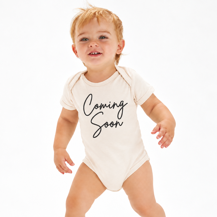 Naturel Coming Soon rompertje voor zwangerschapsaankondiging gedragen door baby.