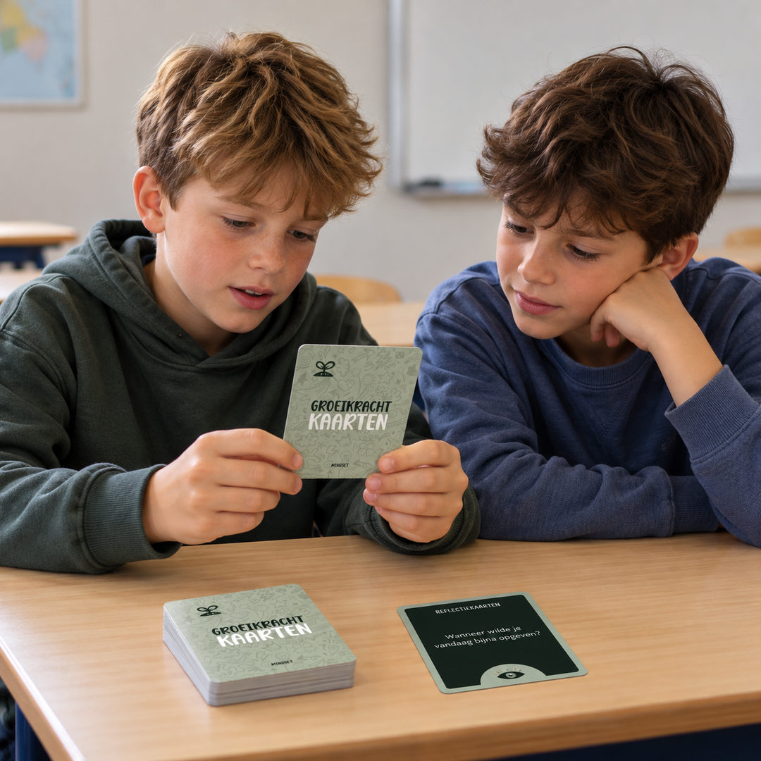 Twee jongens lezen samen een Groeikracht gesprekskaart aan tafel, met een stapel kaarten en een losse reflectiekaart.