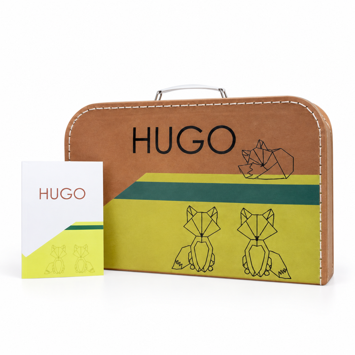 Bruin koffertje met de naam Hugo, getekende dieren en groene en gele vlakken, naast het bijpassende geboortekaartje.