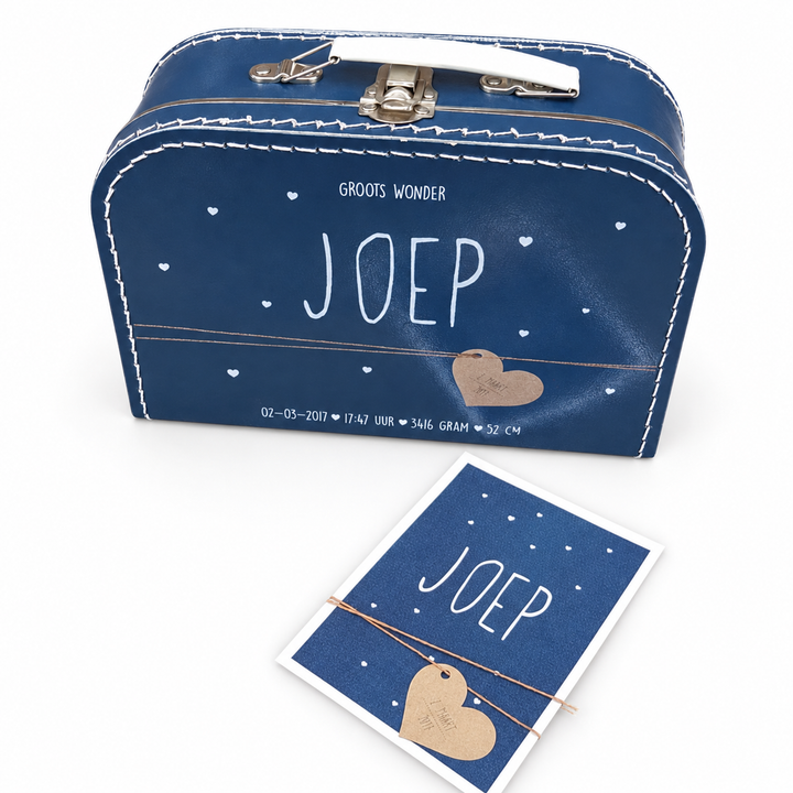 Donkerblauw koffertje met de naam Joep, sterren en een maan, met het bijpassende geboortekaartje ervoor.