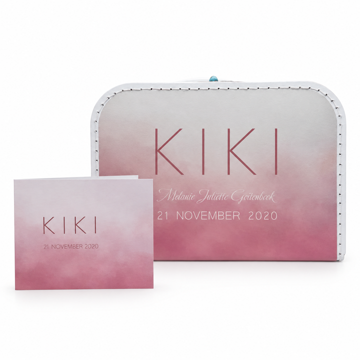 Wit koffertje met roze kleurverloop en de naam Kiki, naast het bijpassende roze geboortekaartje.