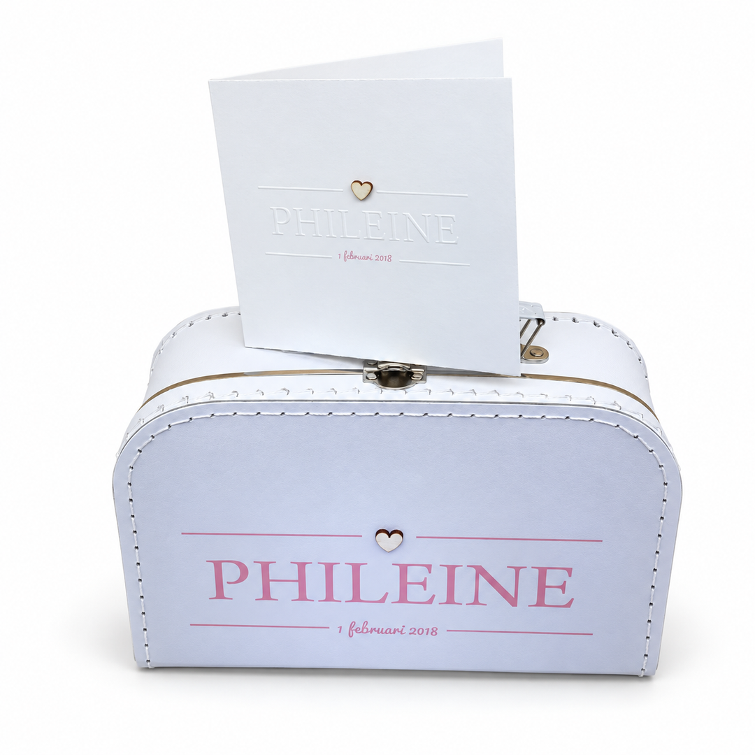 Wit koffertje met de naam Phileine, roze lijnen en een hartje, met het bijpassende geboortekaartje erbovenop.