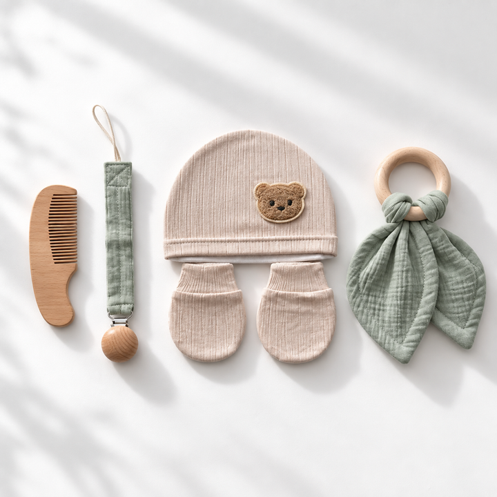 Baby kraamcadeauset met beige muts en wantjes, houten kam, speenkoord en groene bijtring.