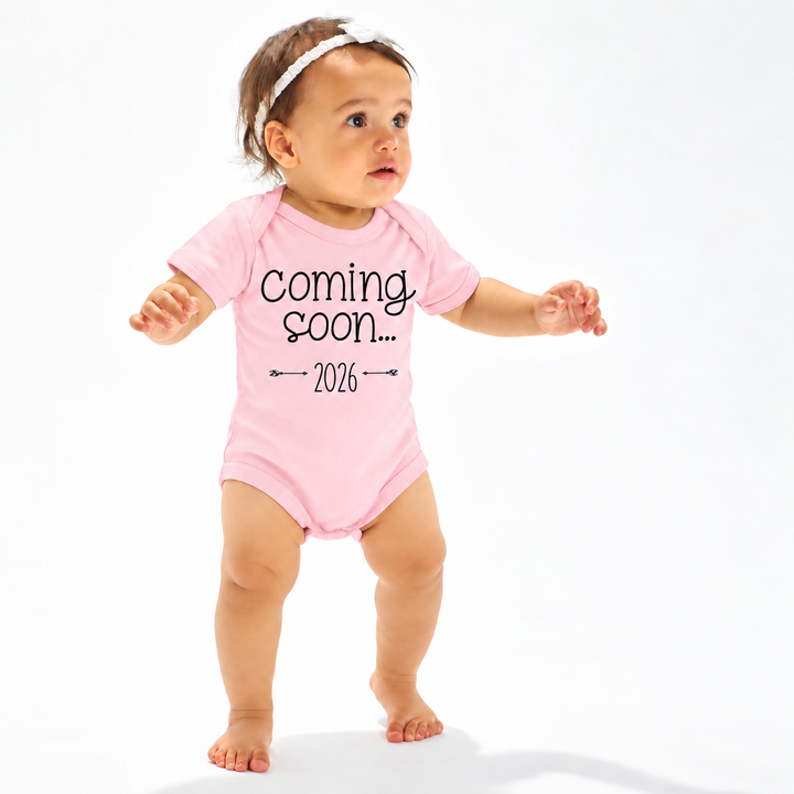 Roze zwangerschapsaankondiging rompertje met Coming Soon en jaartal.