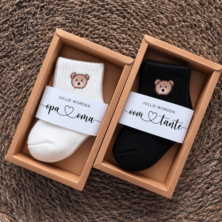 Twee zwangerschapsaankondiging cadeau­doosjes met babysokjes en tekstwikkel